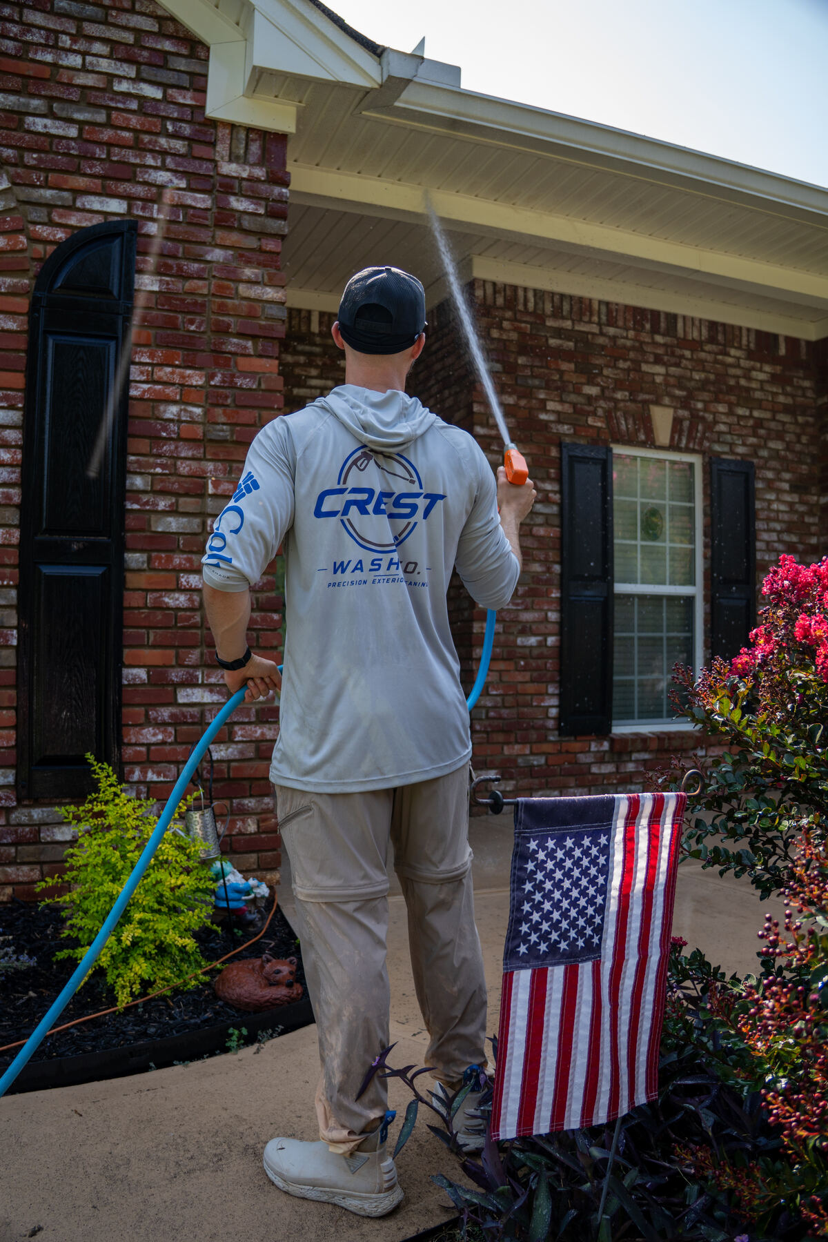 Technician soft washing the brick and soffits of a home